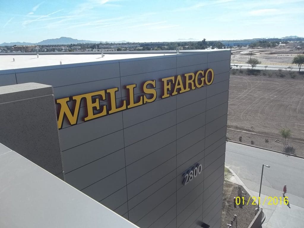 The Wells Fargo building proudly displays its large sign and the number 2800 against a backdrop of clear skies. With a focus on modern design, this iconic structure ensures roof safety while maintaining its commanding presence. The image is dated January 21, 2016.