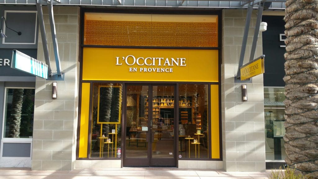 The exterior view of the L'Occitane en Provence store in Scottsdale features a bright yellow facade and large glass doors, inviting shoppers into its elegant quarters.