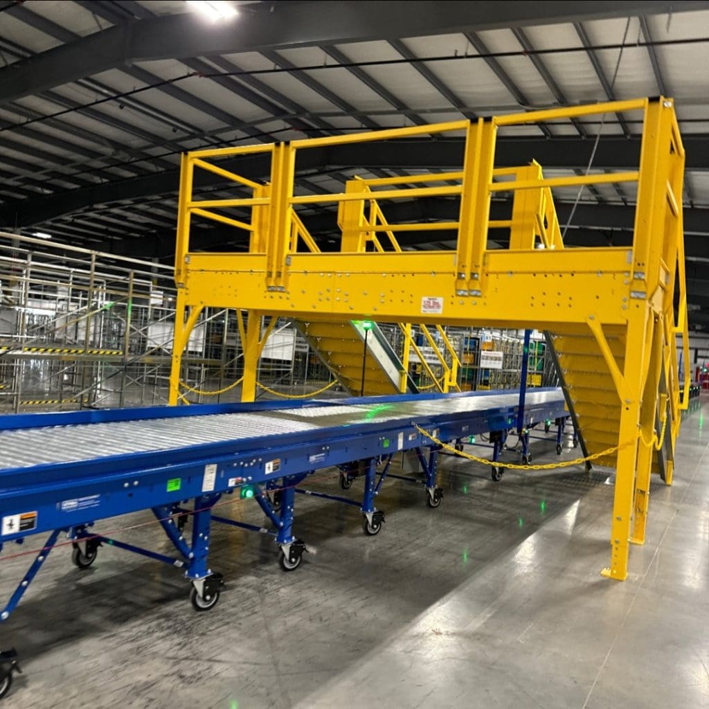 The WKY3 blue conveyor belt, complete with a yellow safety staircase, stands prominently in the expansive warehouse setting.