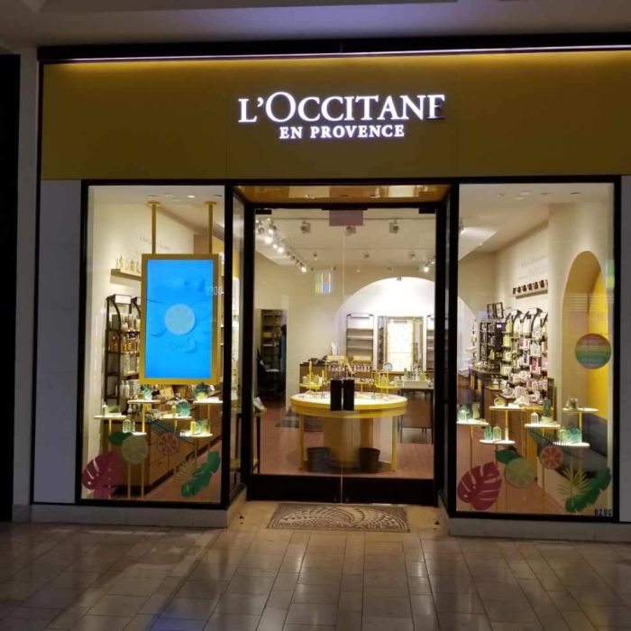 The storefront of L'Occitane en Provence in Mission Viejo features a striking yellow and black sign, large glass windows, and enticing displays of products inside, offering a delightful shopping experience.